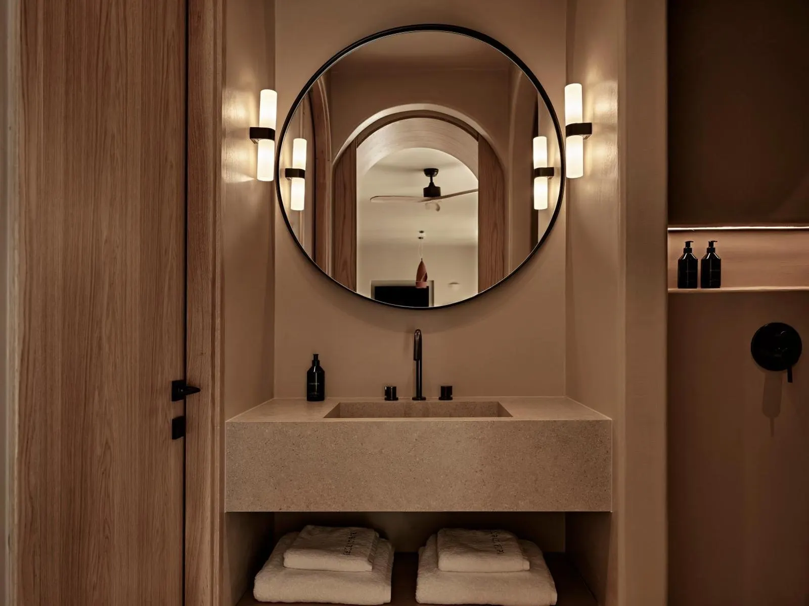Round mirror above stone bathroom vanity