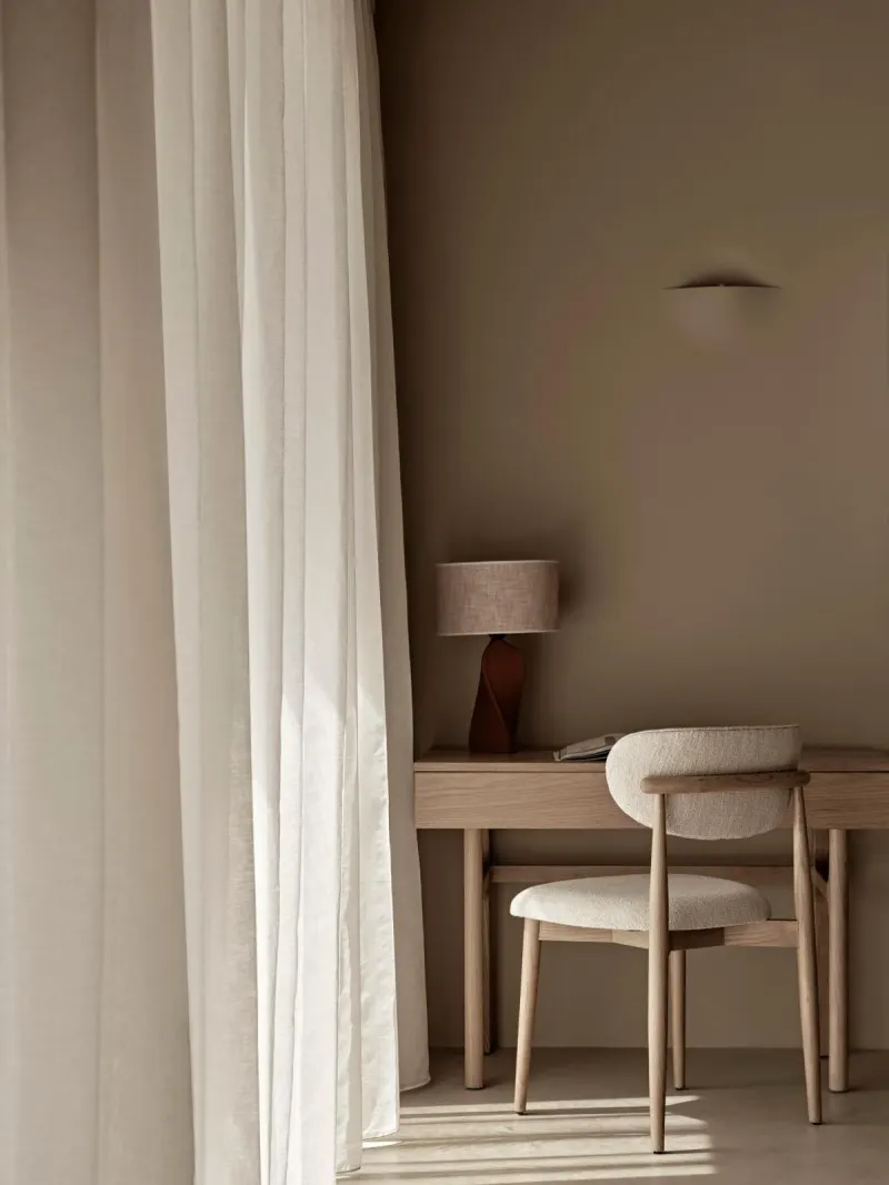 Desk and chair beside sheer curtains