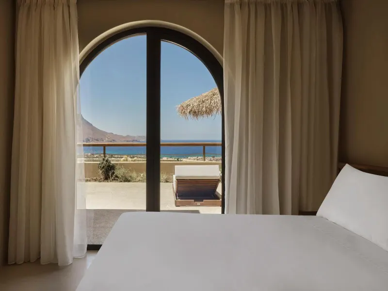 Bed with arched window framing sea view