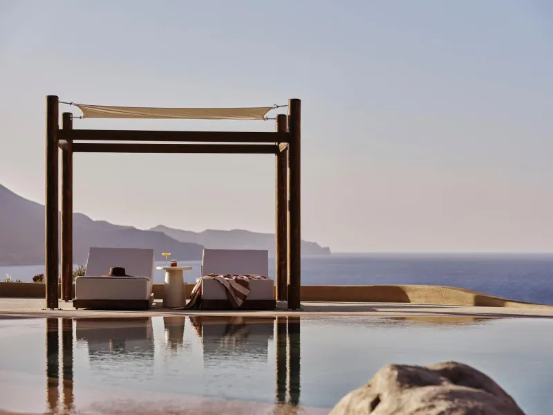 Poolside daybeds under wooden pergola by sea