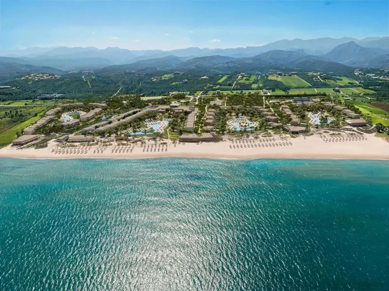 Aerial view of resort along sandy beach and mountains