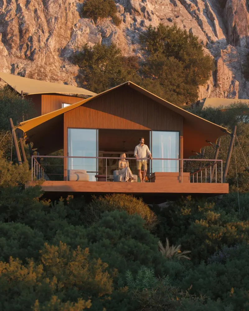 Couple standing on deck of tented suite at sunset