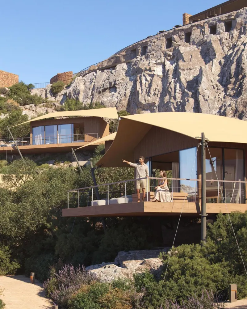 Couple on balcony of tented villas against cliffs
