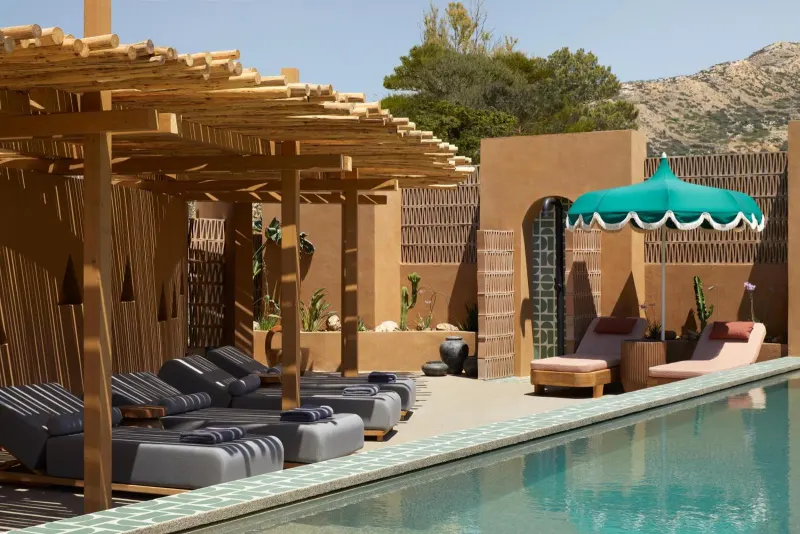 Poolside loungers under wooden pergola with teal umbrella