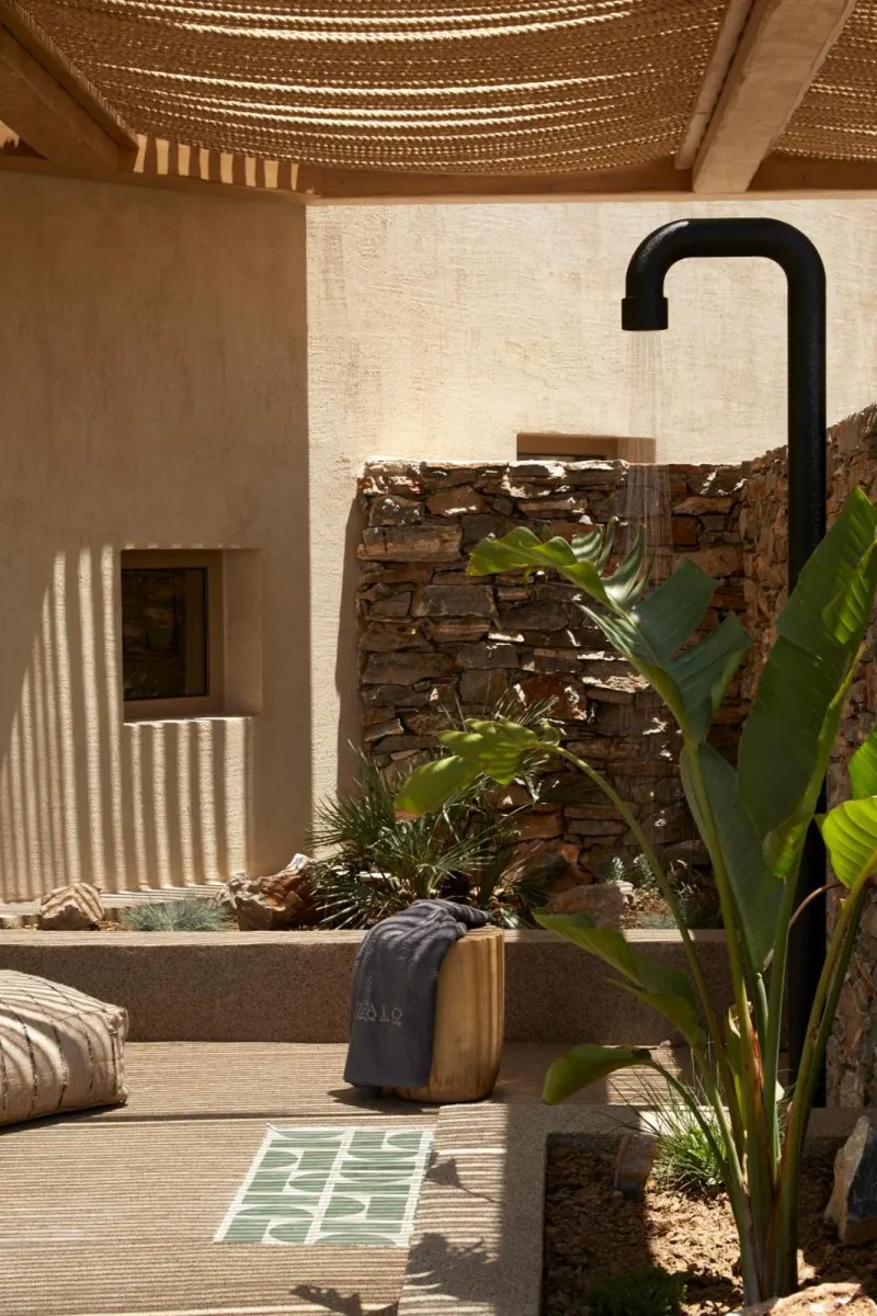 Outdoor shower area with stone wall and plants