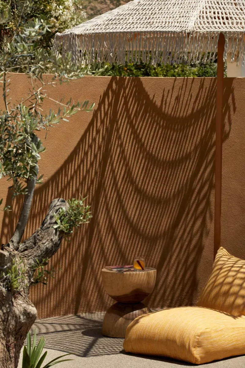 Shadow patterns from macrame umbrella on terracotta wall