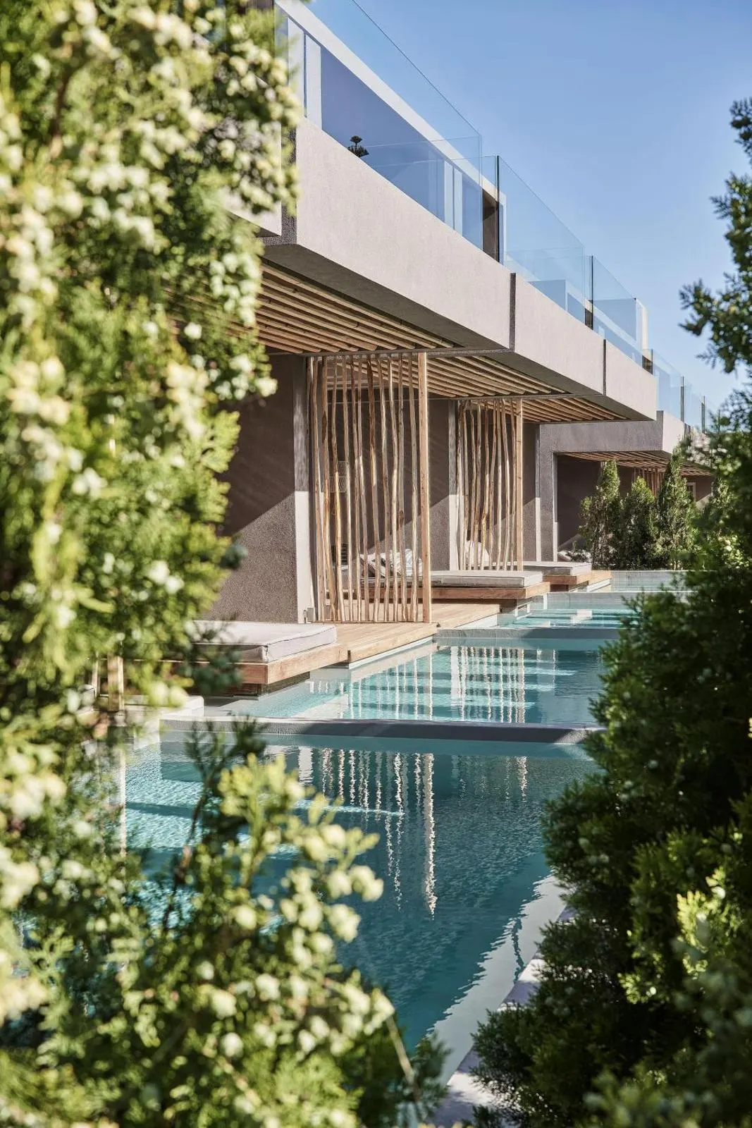 Infinity pool alongside modern wooden hotel facade