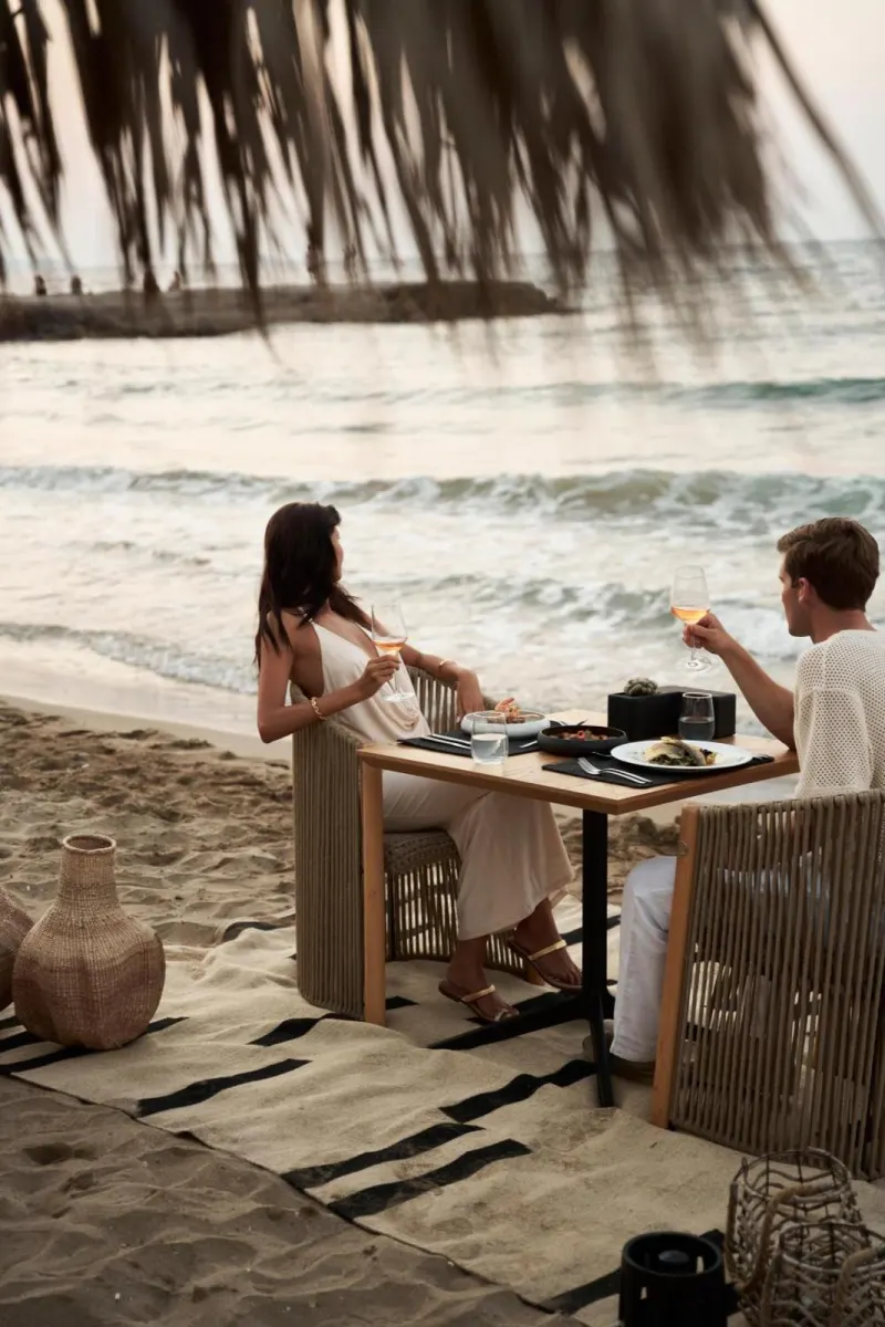 Couple dining on beach at sunset