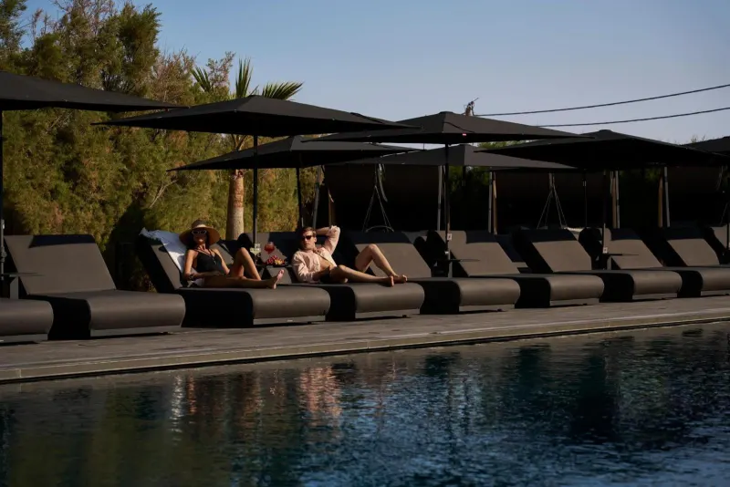 Guests relaxing on loungers by pool at sunset
