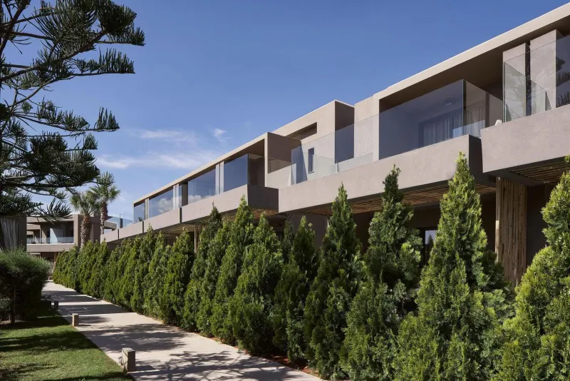 Modern hotel exterior with manicured hedges and balconies