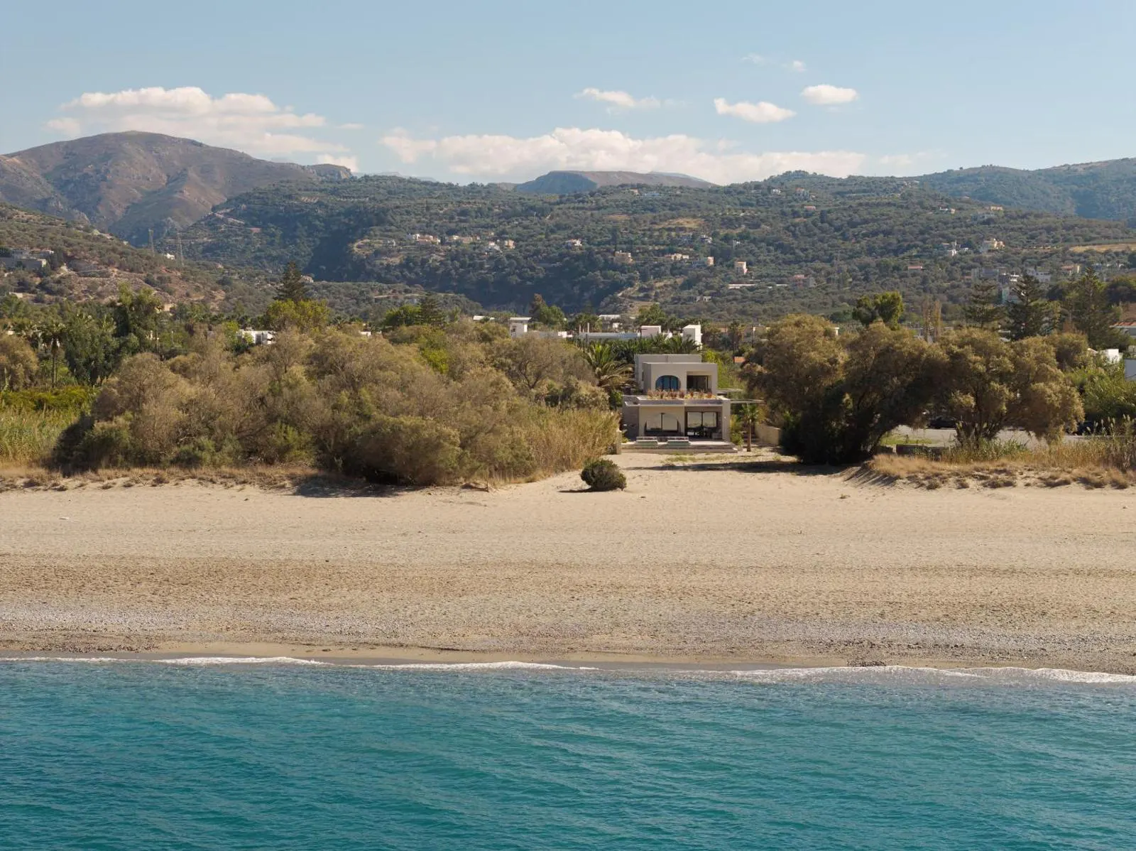 Villa nestled among dunes with mountain backdrop