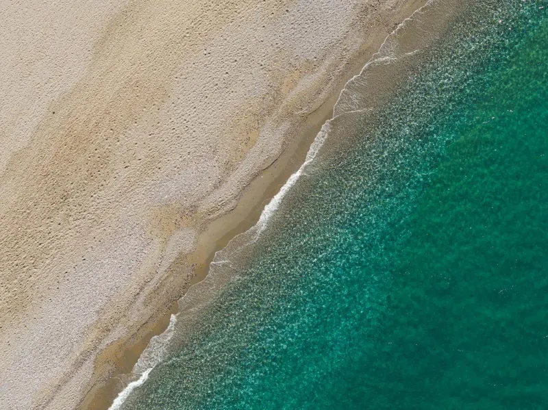 Aerial view of turquoise waves on sandy beach