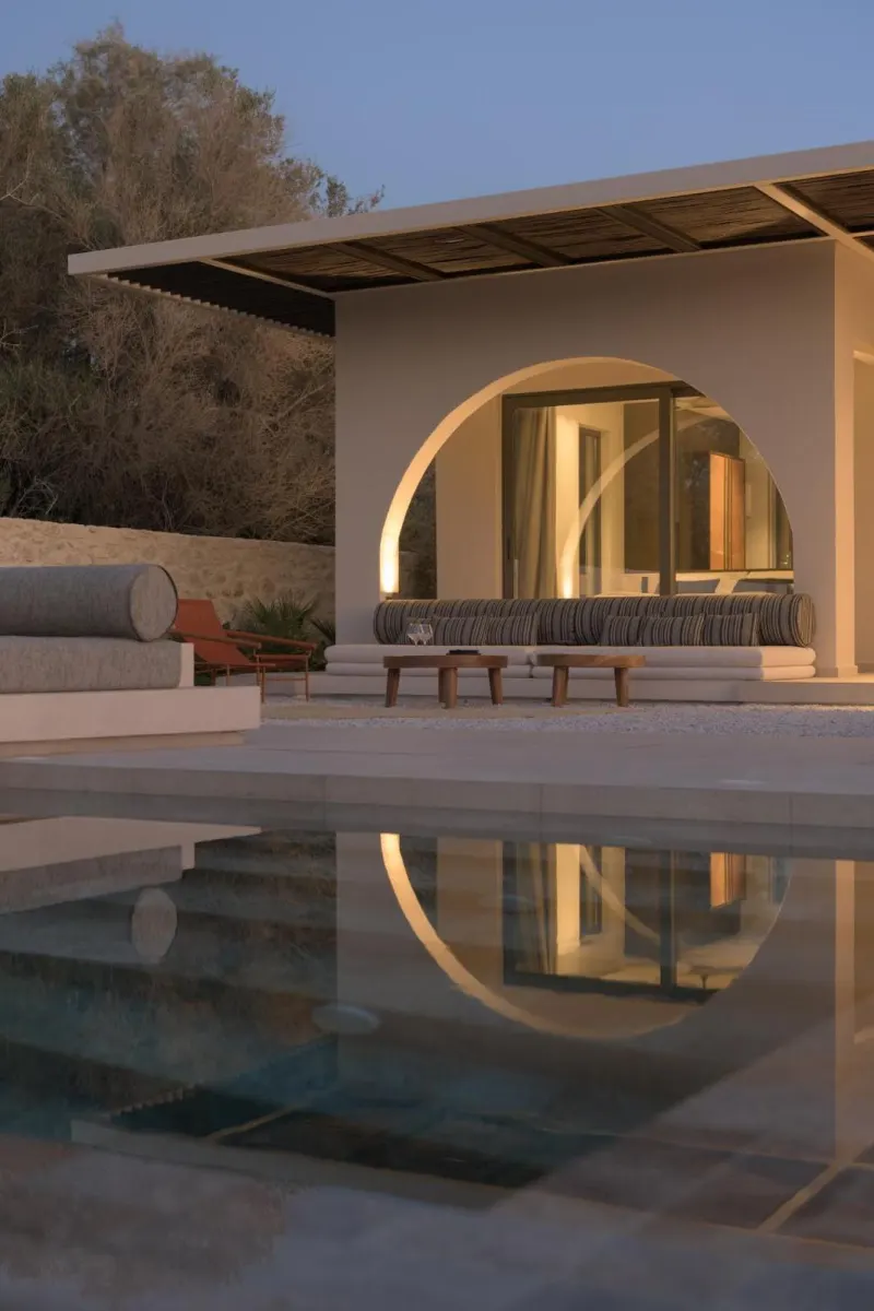 Arched poolside lounge reflected in water at dusk