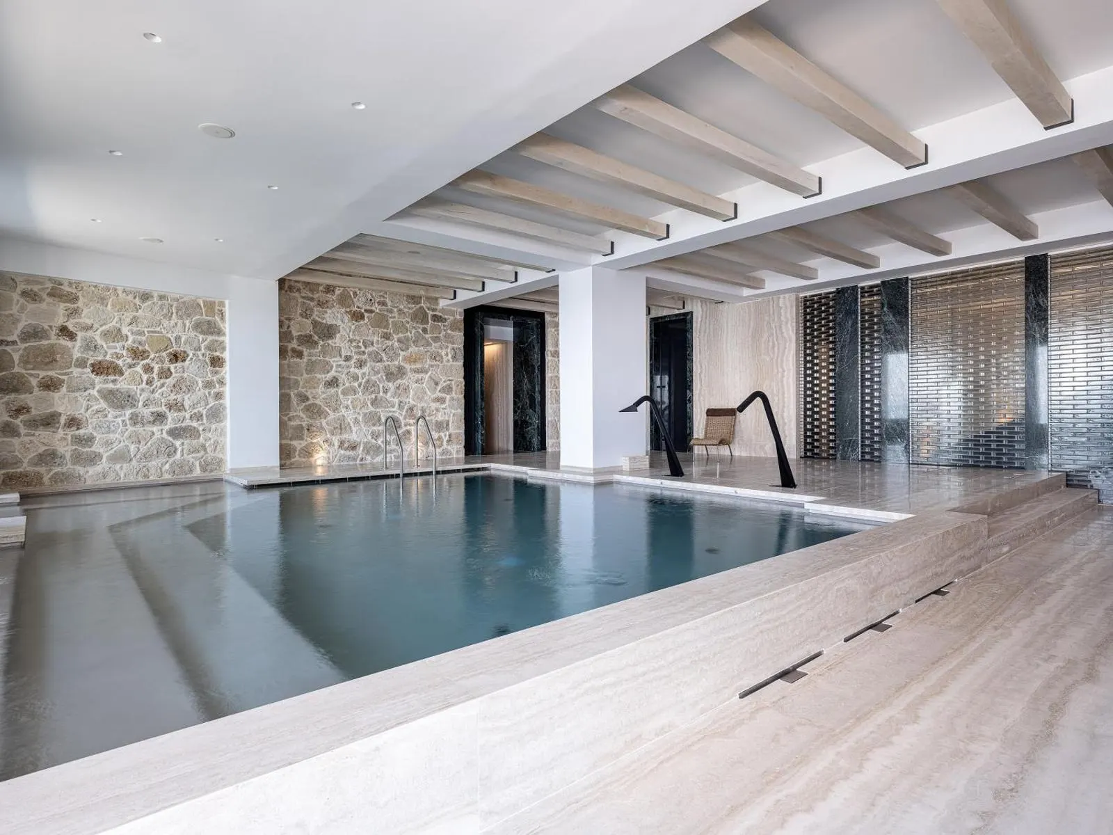 Indoor pool with stone wall and wood beams