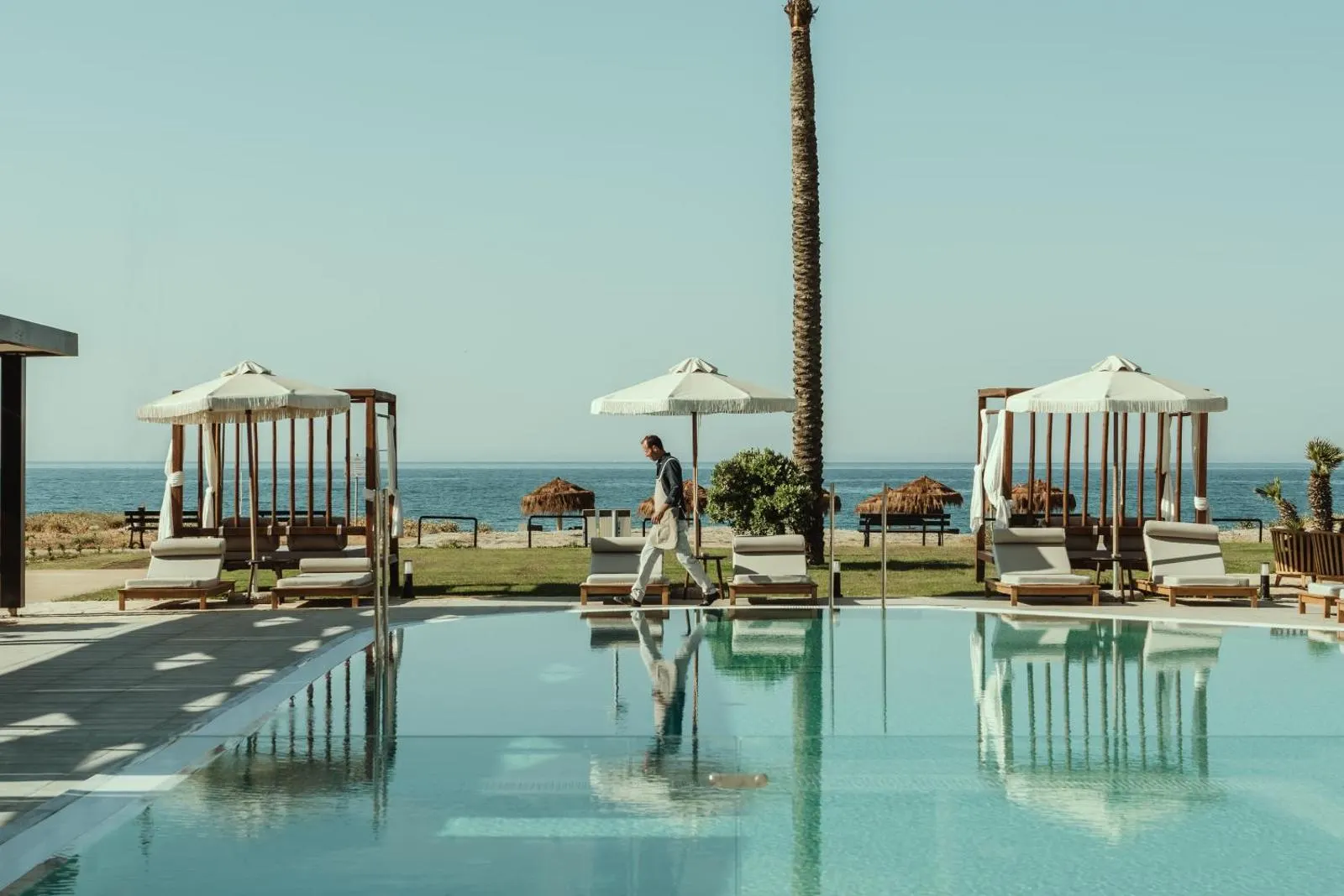 Poolside cabanas with sea view and palm tree