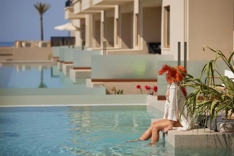 Woman dipping feet in infinity pool by building