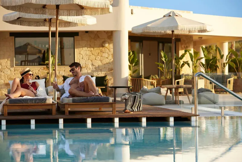 Couple relaxing on poolside loungers near building