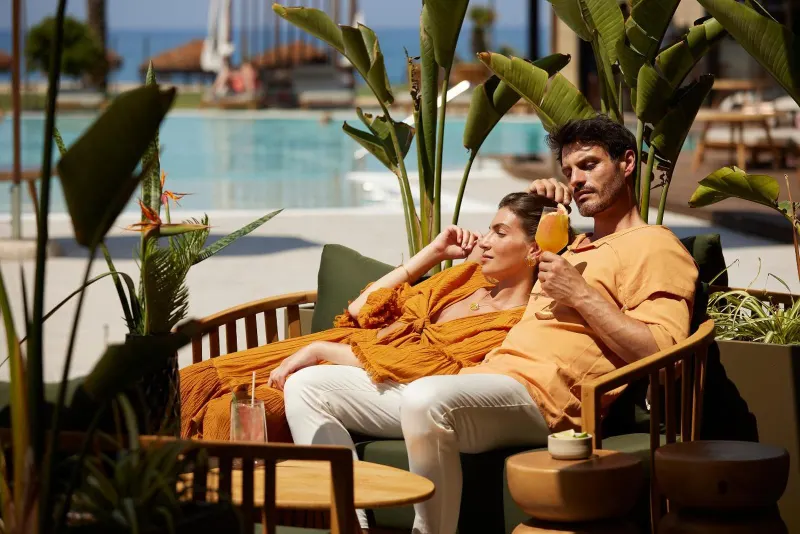 Couple in robes enjoying drinks by pool