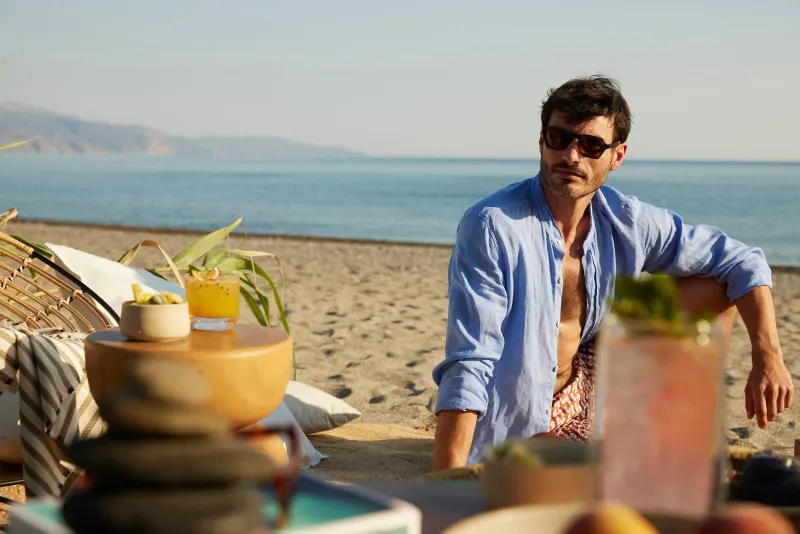 Man standing at beach picnic table with drinks