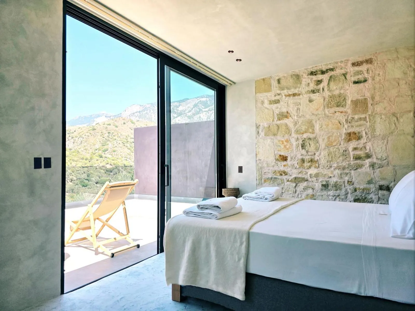 Bedroom with stone wall and mountain view terrace
