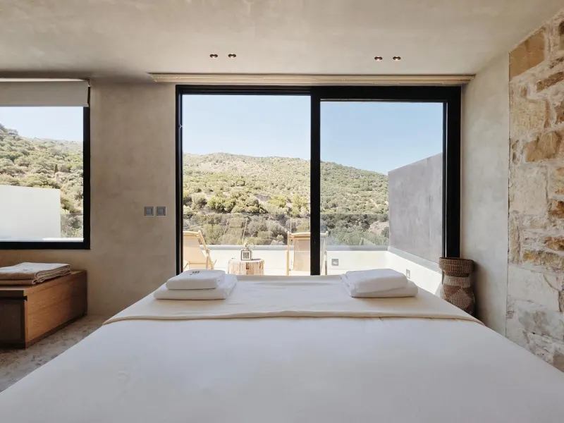Bed facing large window with hillside view