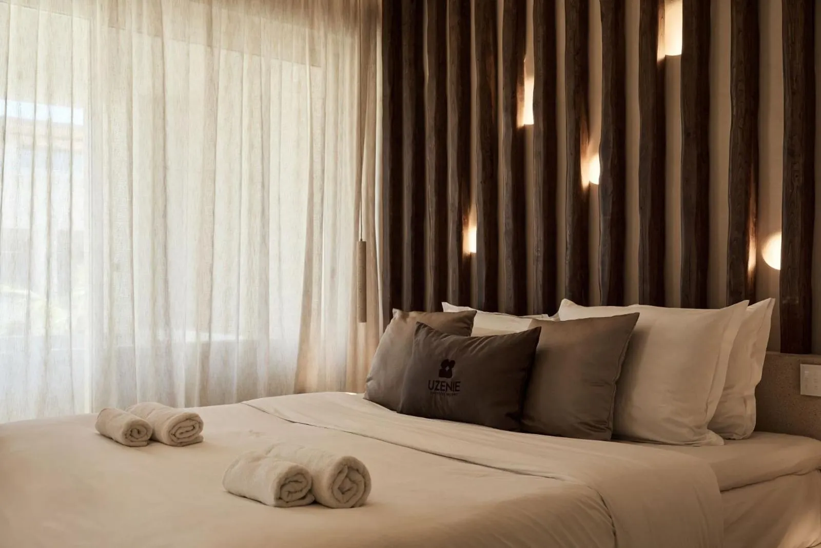 Bed with towels beneath textured wood headboard