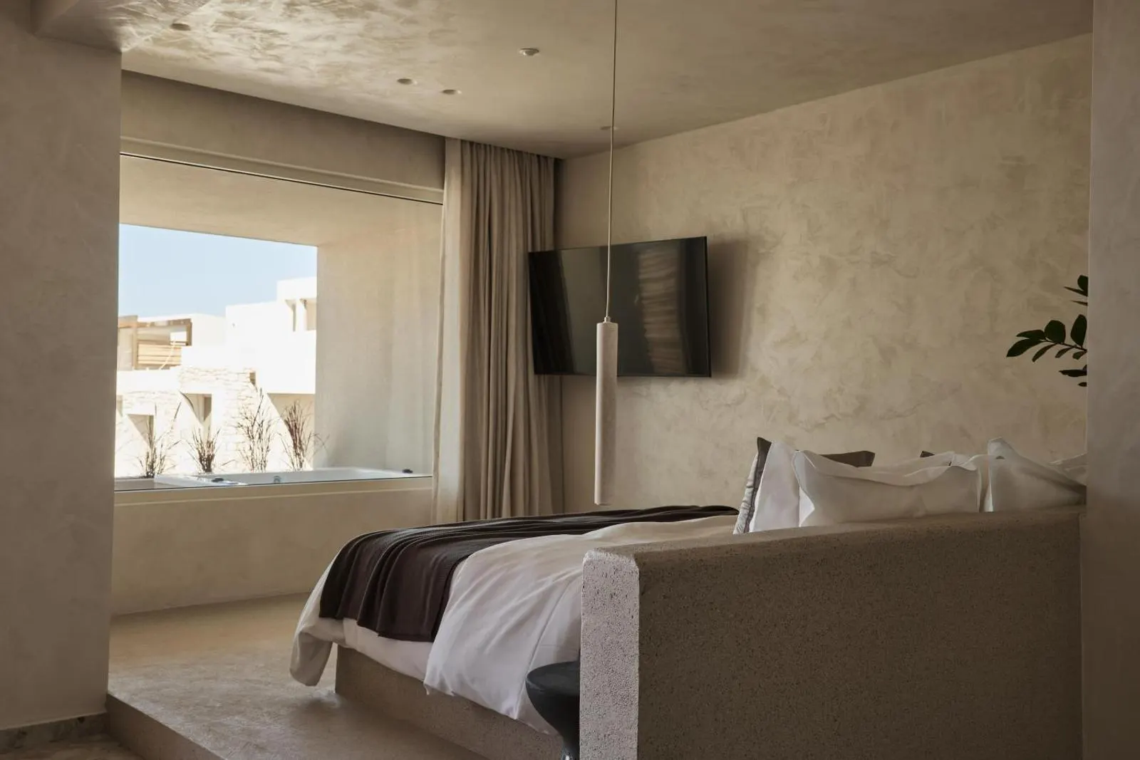 Bedroom with window overlooking whitewashed buildings