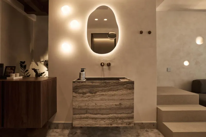Stone vanity with mirror beside wooden steps