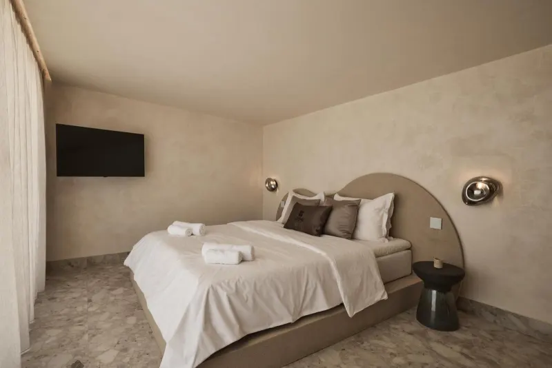 Bed with curved headboard and wall sconces
