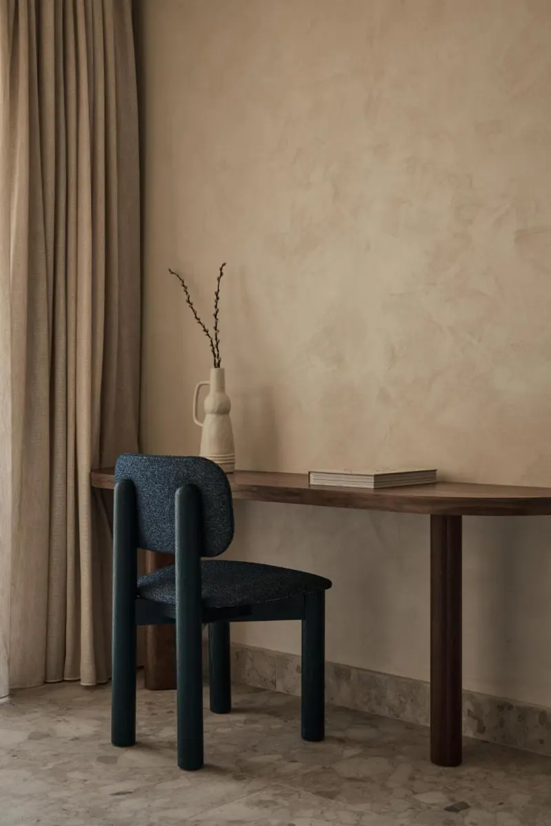 Wooden desk and dark chair against textured wall