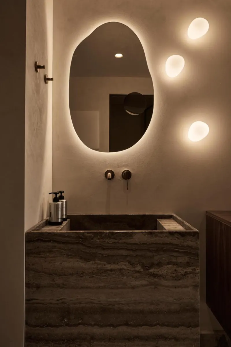 Illuminated stone sink with glowing mirror at night