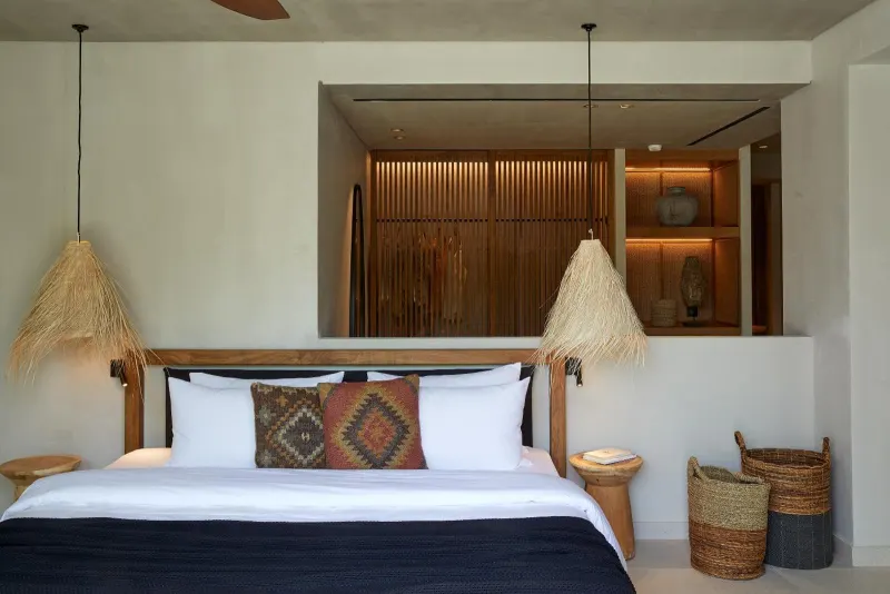 Bed with woven pendant lights and patterned pillow