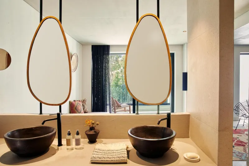 Bathroom with dual teardrop mirrors and dark sinks