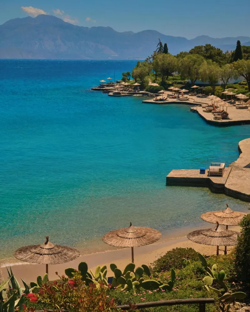 Turquoise sea with beach umbrellas and mountains