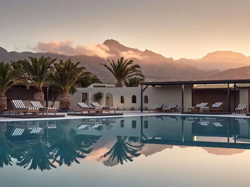 Sunset view of pool with mountains and palm trees