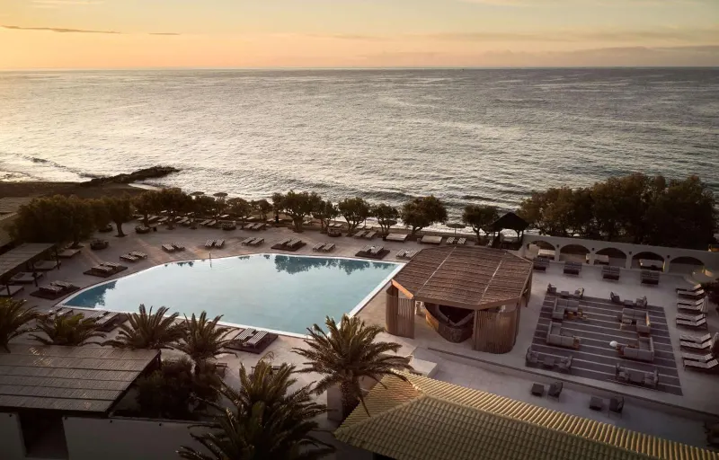 Aerial view of pool beside the sea at sunset