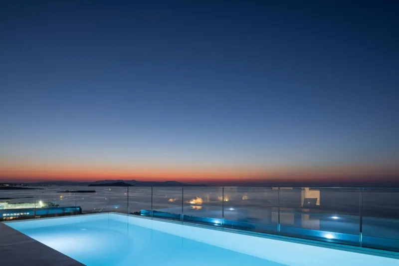 Rooftop infinity pool glowing at twilight over the sea