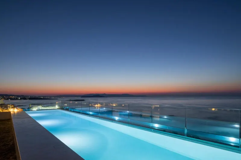 Infinity pool illuminated at dusk with sea horizon