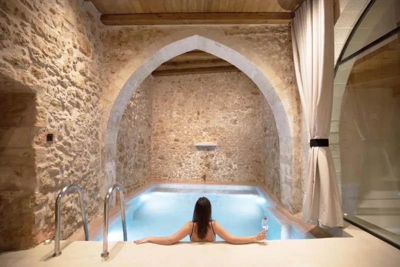 Woman relaxing in stone-arched indoor plunge pool