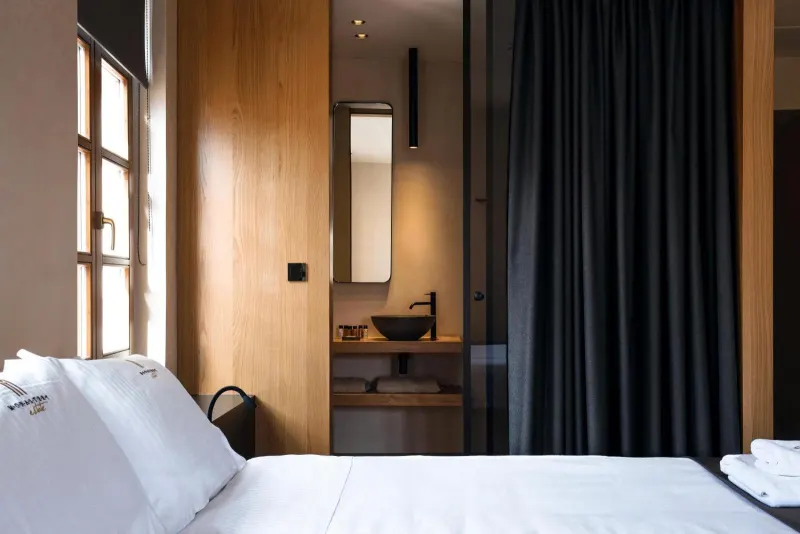 Bedroom with dark curtain and glass-walled bathroom