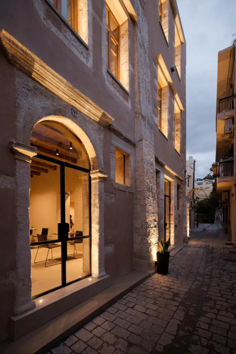 Illuminated stone building facade on cobblestone street at dusk