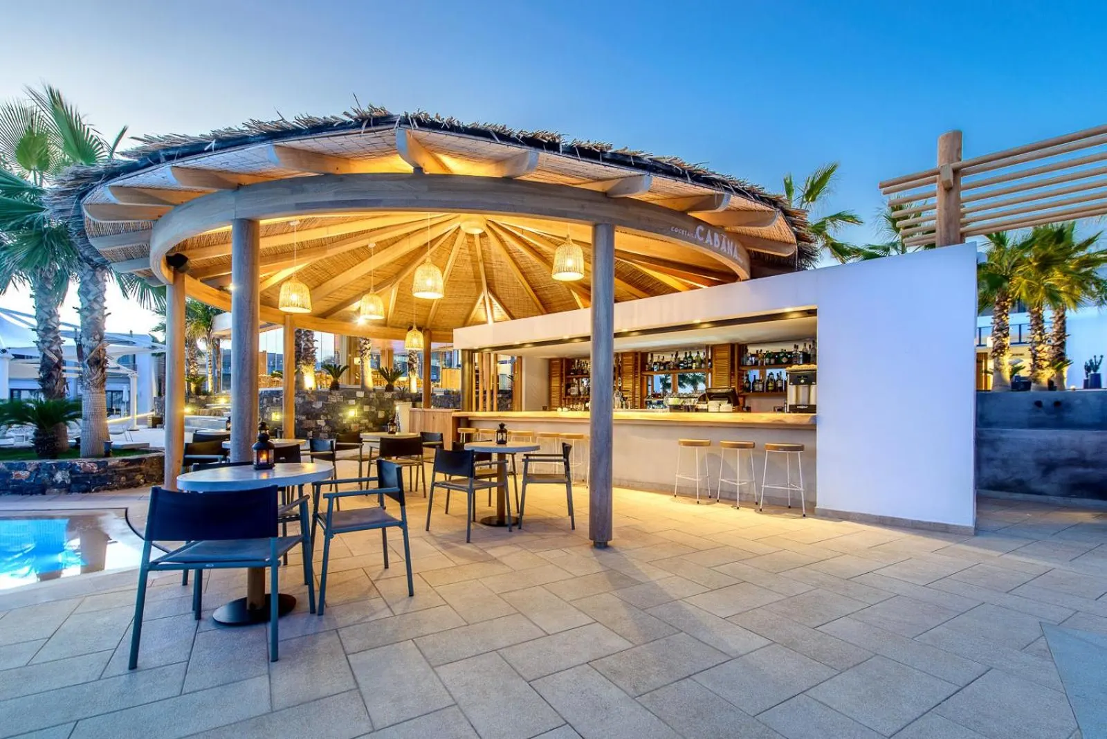 Poolside bar with wooden thatched canopy at dusk