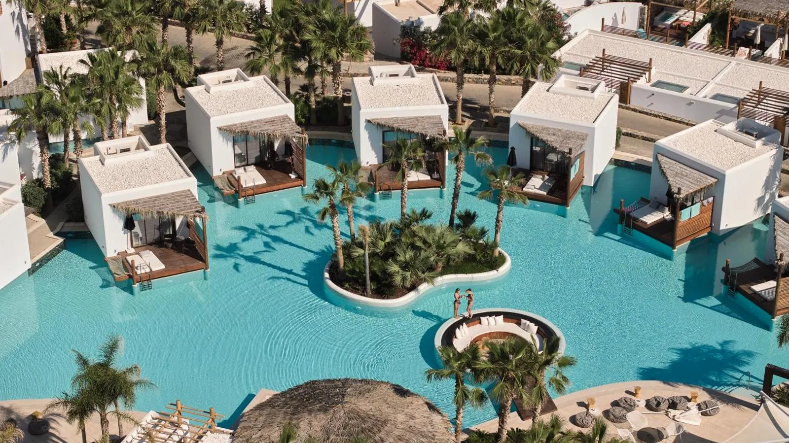 Aerial view of pool cabanas surrounded by turquoise water