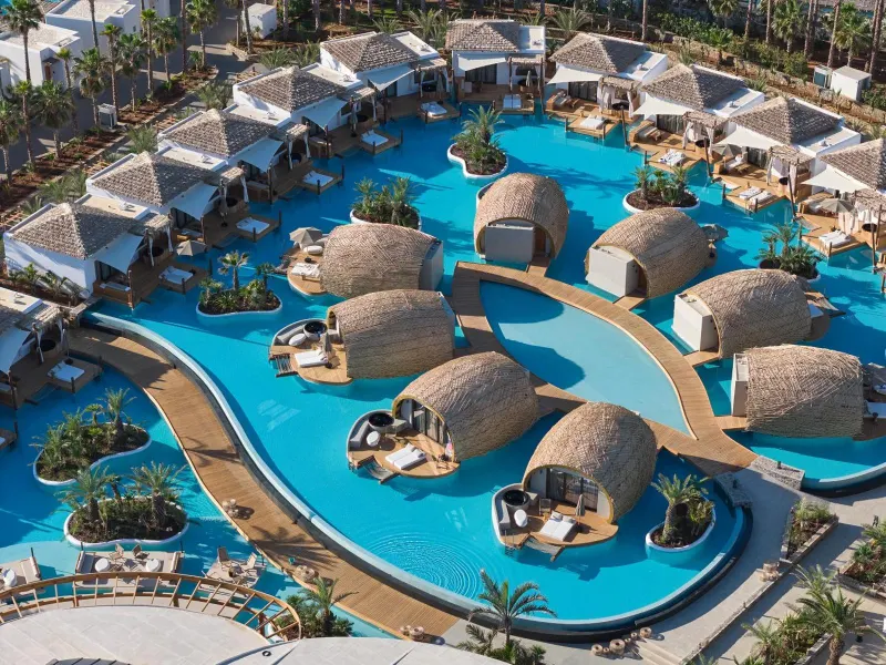 Aerial view of thatched-roof overwater bungalows and pool complex
