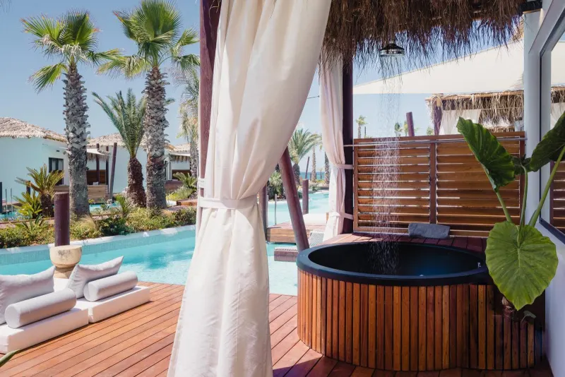 Private outdoor hot tub on wooden deck with curtains