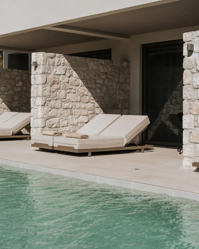 Poolside loungers against stone wall