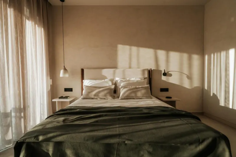 Bedroom with green throw and wall sconces