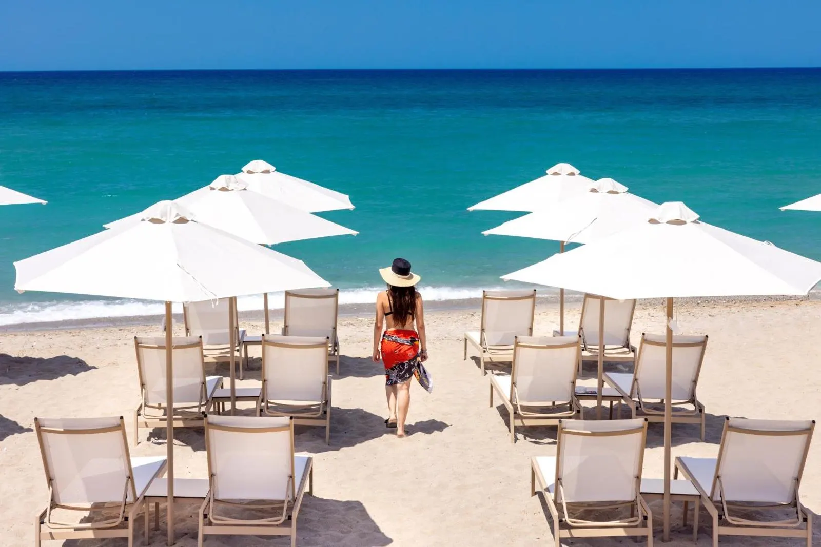 Woman walking toward beach loungers and umbrellas