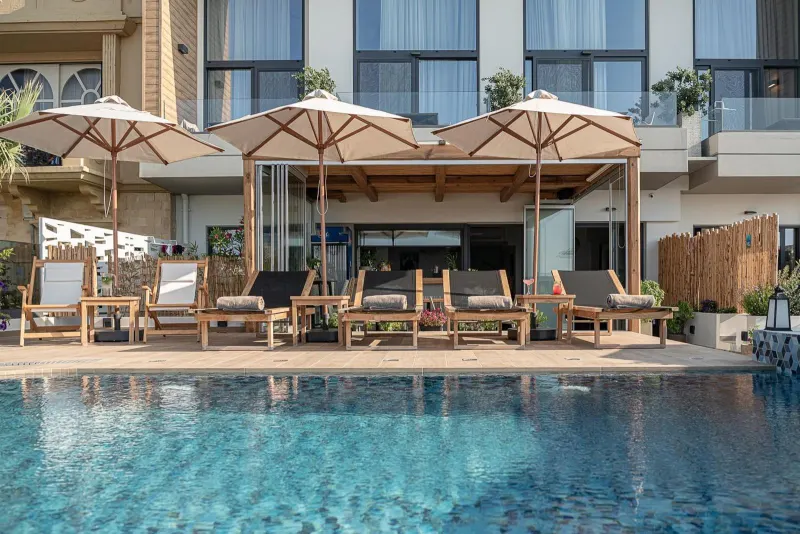 Poolside loungers under umbrellas by building