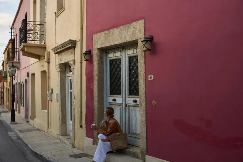 Woman sitting by colorful pink building door